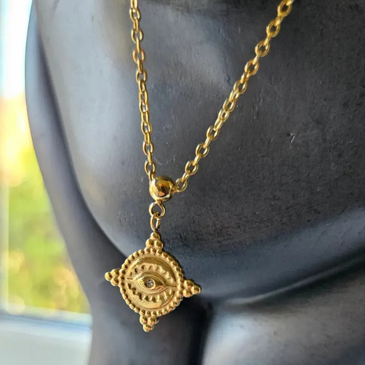 evil eye Gold necklace with a decorative pendant on a mannequin.