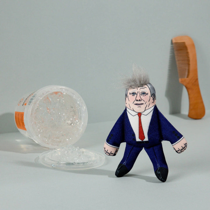 Toy figure of a person in a suit with a comb and container on a gray background
