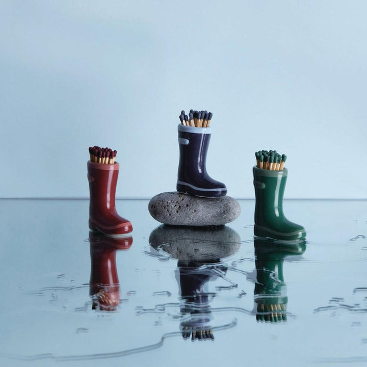 Three pairs of rain boots matches on a reflective surface with a light blue background