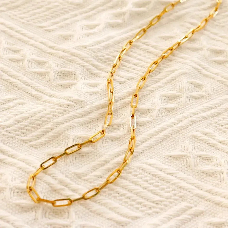Gold chain  link necklace on a textured beige background