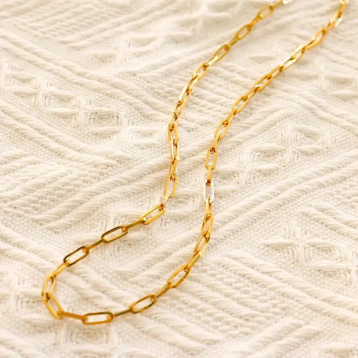 Gold chain  link necklace on a textured beige background
