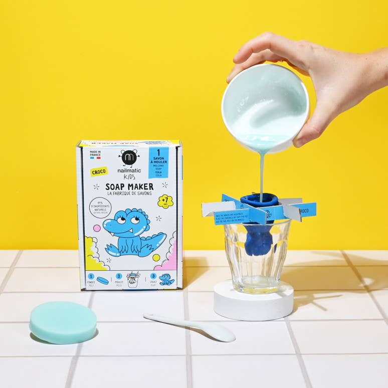Soap maker kit with a hand pouring liquid into it against a yellow background