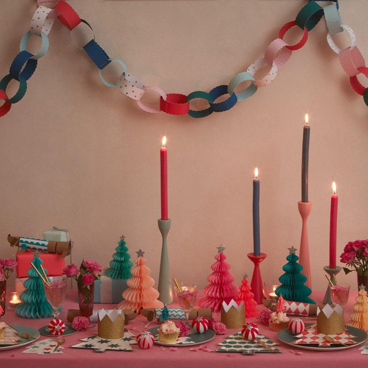 Decorative christmas table setting with colourful candles, paper trees, and paper chains and peppermint candy surprise balls