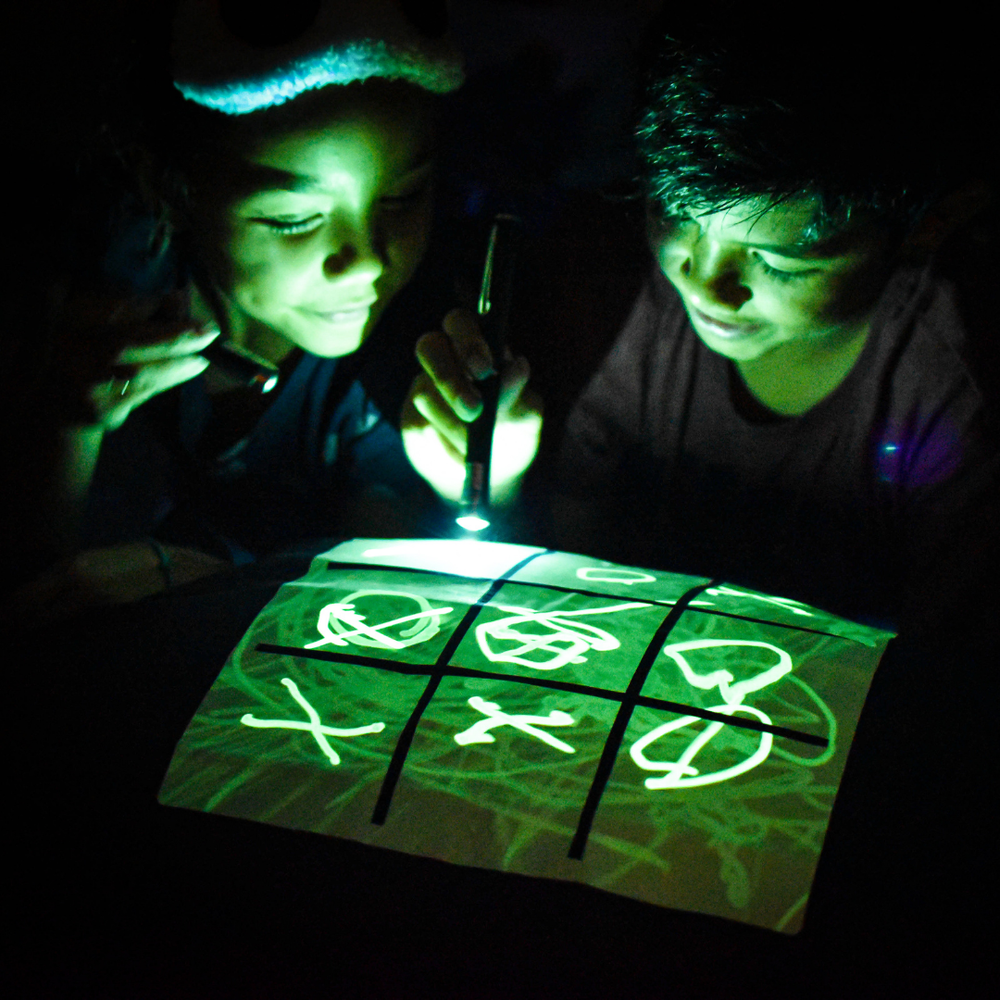 Two children playing a game on a glowing board in the dark.