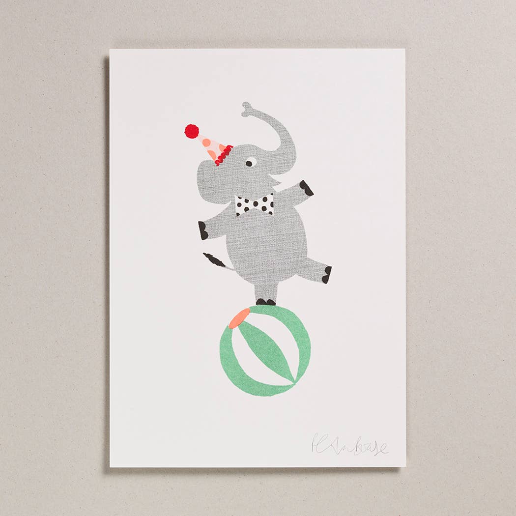 A greetings card with a grey elephant balancing on a green and white ball
