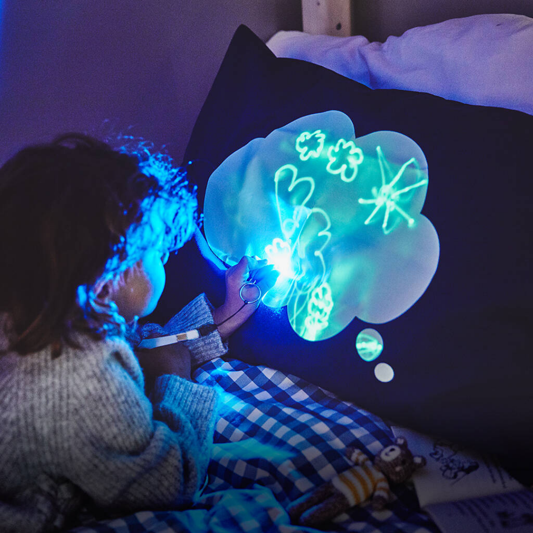 Child playing with a glowing light pillow in a dark room