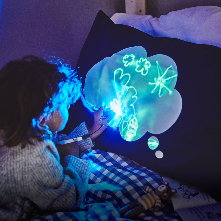 Child playing with a glowing light pillow in a dark room
