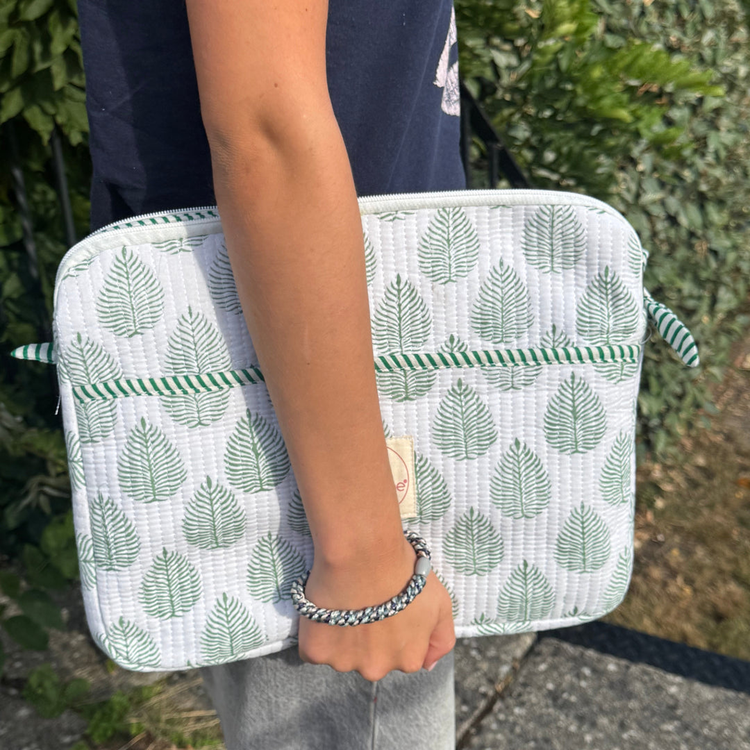 Person holding a laptop casewith green leaf pattern outdoors