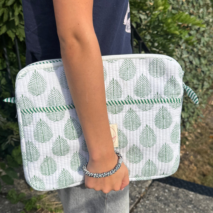 Person holding a laptop casewith green leaf pattern outdoors