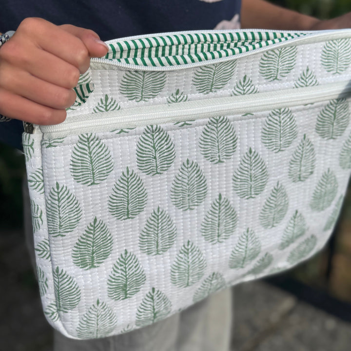 Person holding a white pouch with green leaf pattern