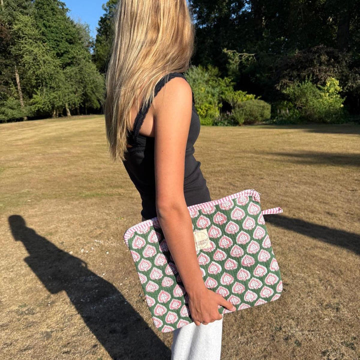 Person holding a green patterned bag outdoors on a grassy area