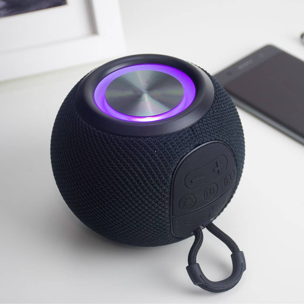 Black portable speaker with purple light on a white surface