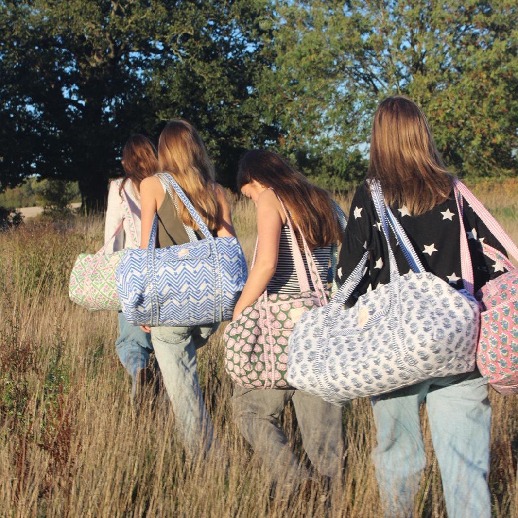 Four women walking in a field with patterned bags.