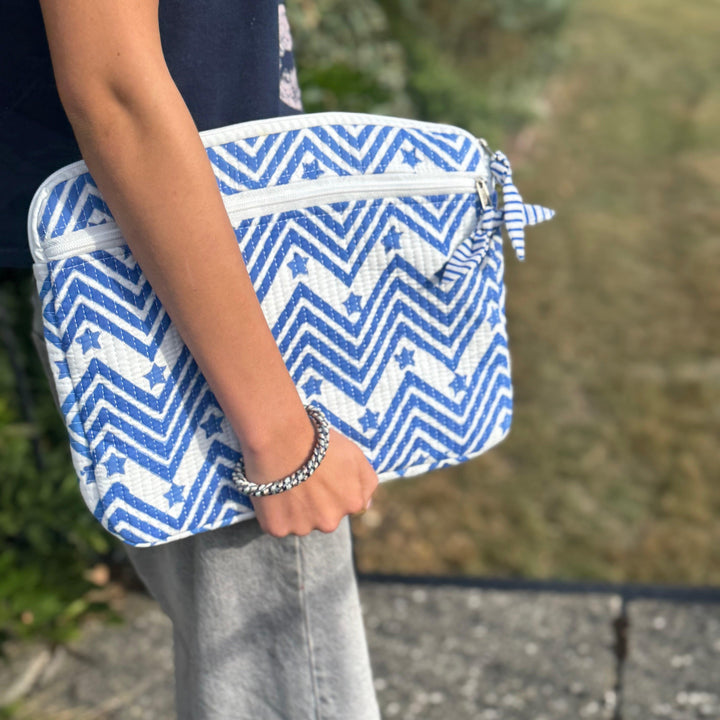 Person holding a blue and white zigzag patterned bag outdoors for laptop