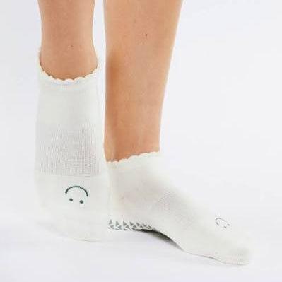 White socks with smiley face designs worn by a person on a white background