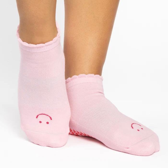 Pink socks with smiley face design worn by a person on a white background