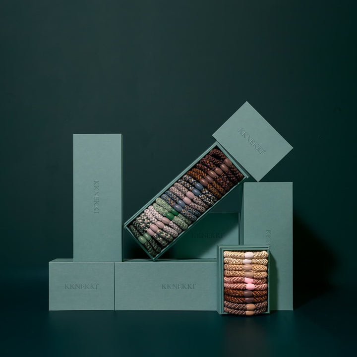 Stack of green boxes with a smaller box containing jewelry on a dark background
