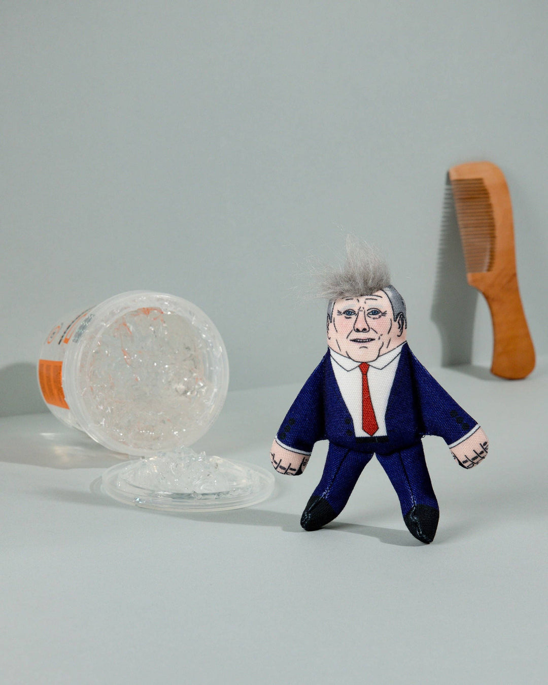 Toy figure of a person in a suit with a comb and container on a gray background