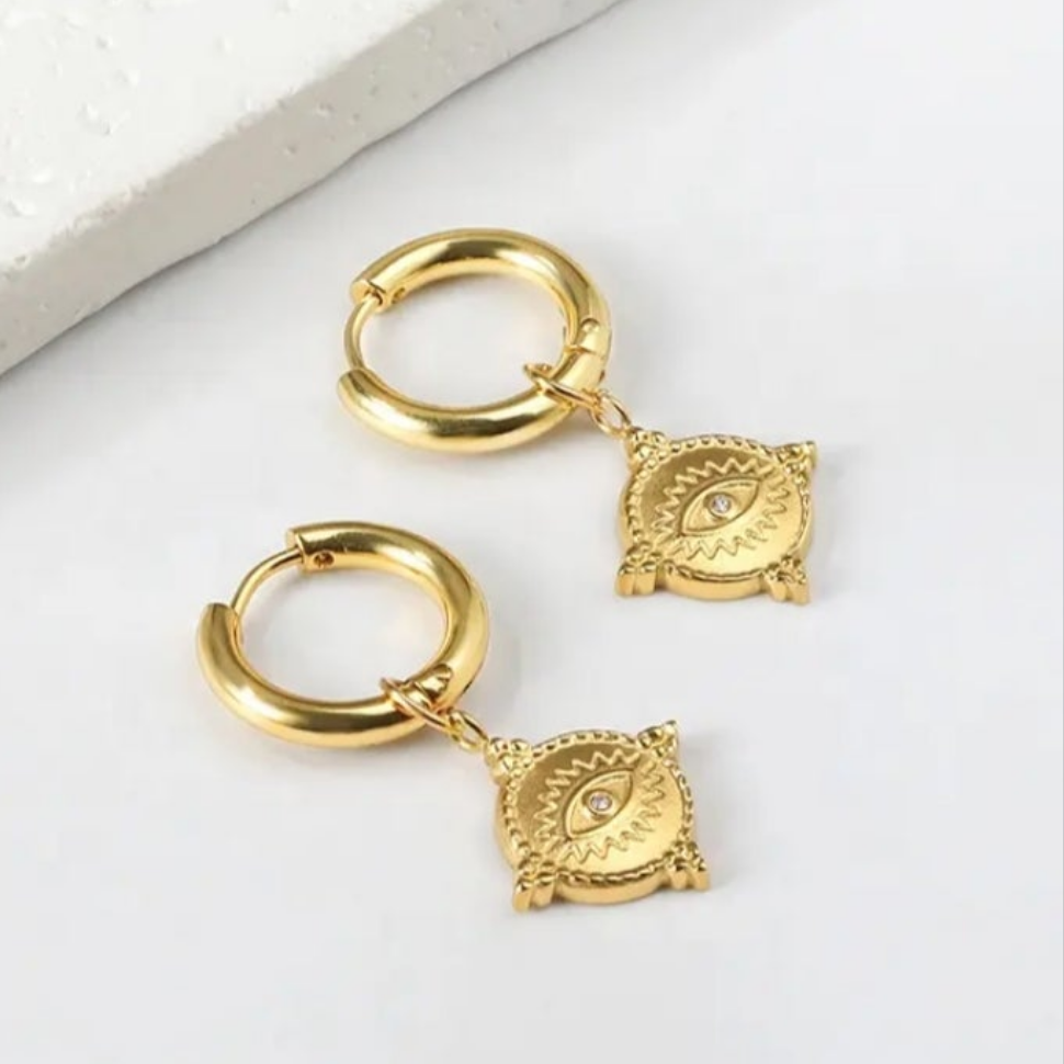 Gold hoop earrings with decorative elements on a white background