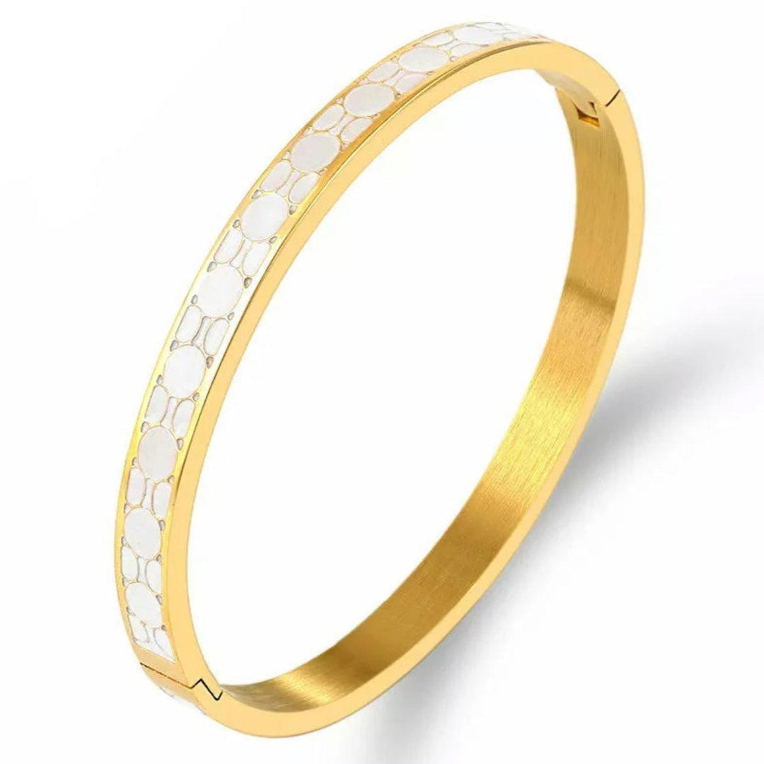 A gold-colored bracelet with white enamel patterned details, made from stainless steel with a PVD coating.