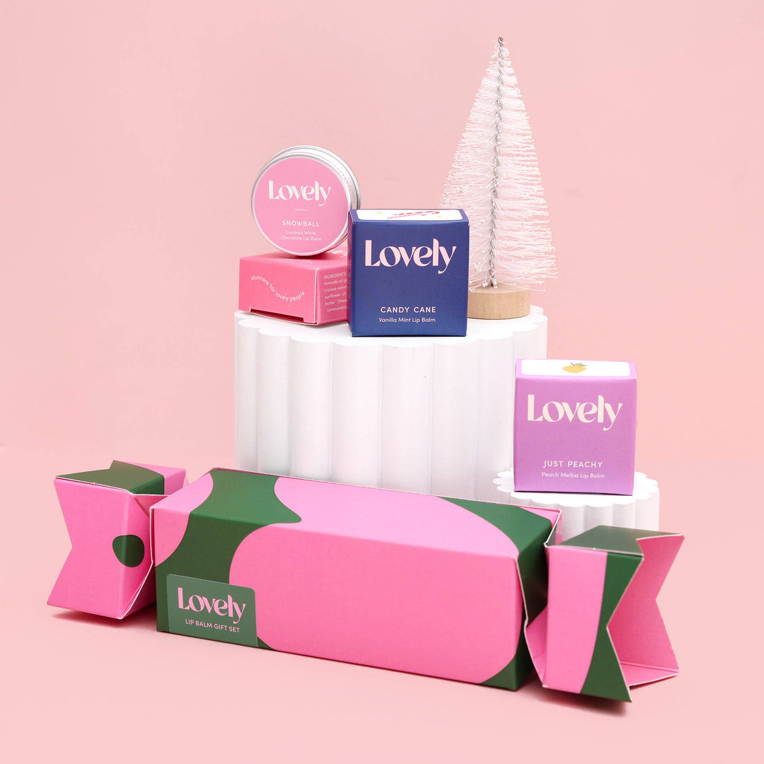 Collection of 'Lovely' branded products including a cracker, box, and small tree on a pink background