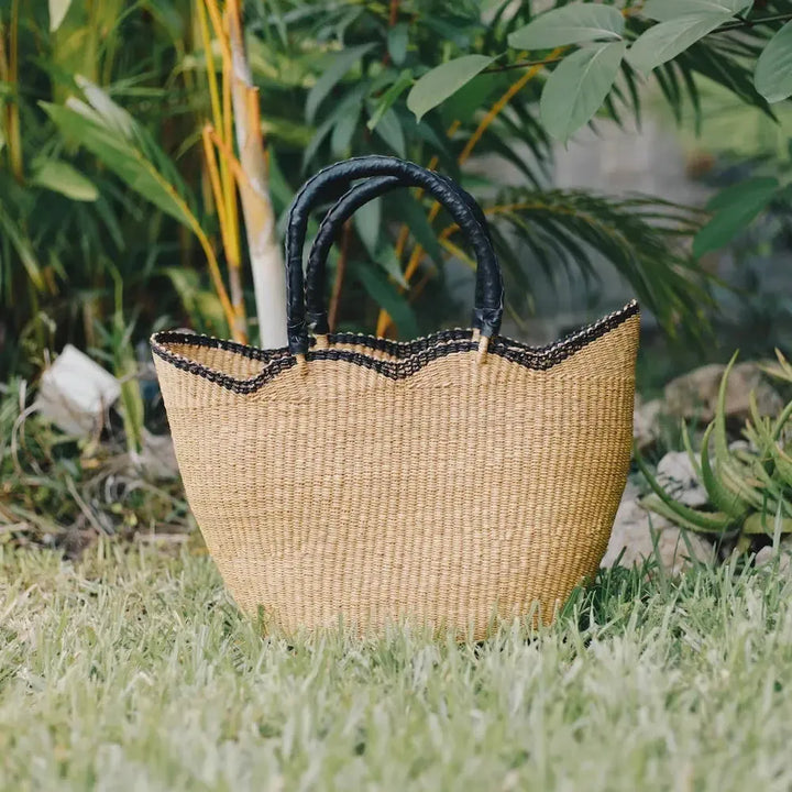 Woven basket with black handles on grass