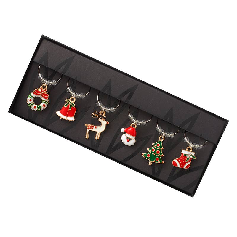 Six Christmas-themed wine glass charms displayed in a black presentation box. The charms include a wreath, bell, reindeer, Santa hat, Christmas tree, and stocking, each with a silver-tone chain loop.